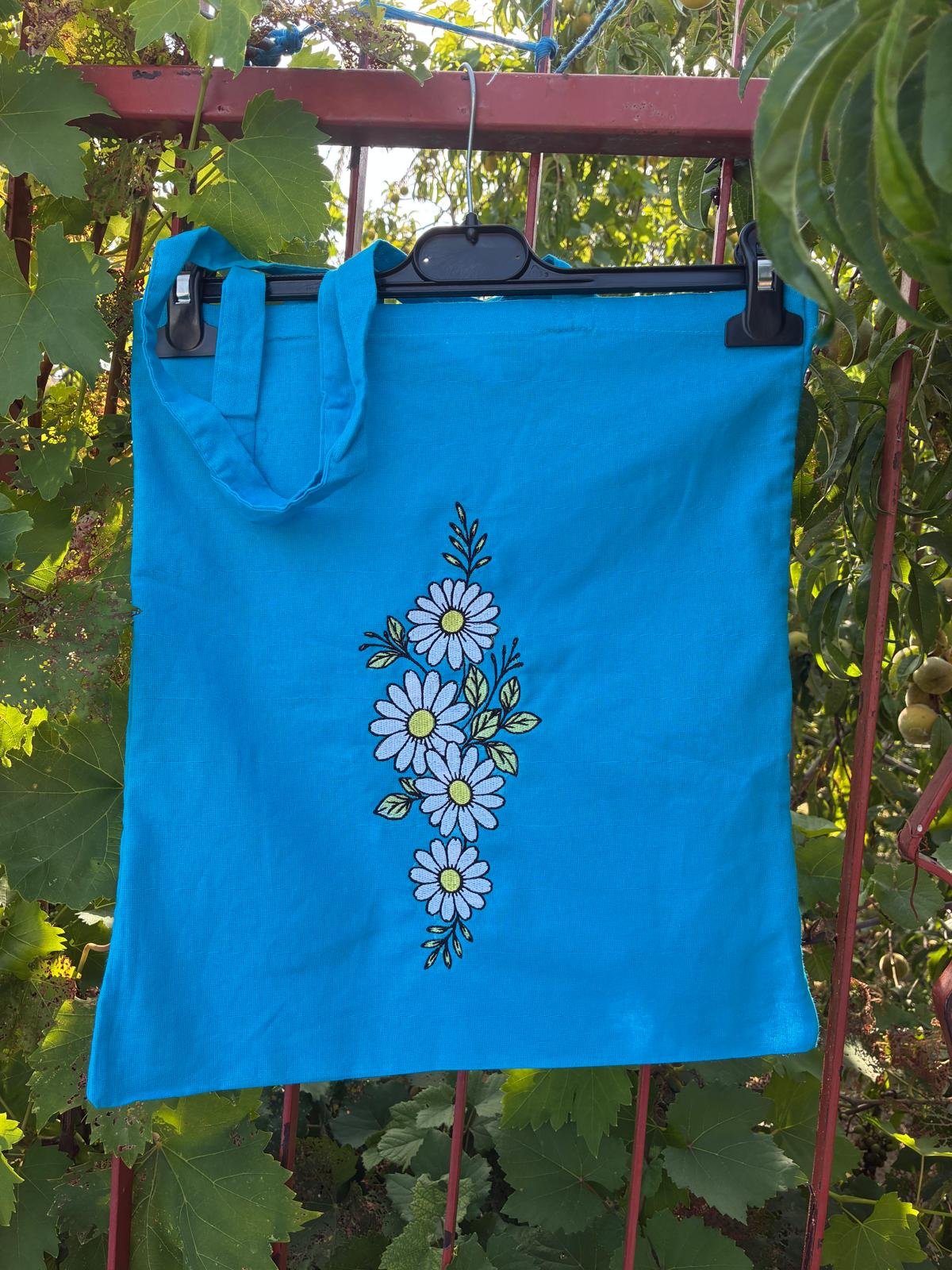 Tote azzurra con composizione di margherite ricamate